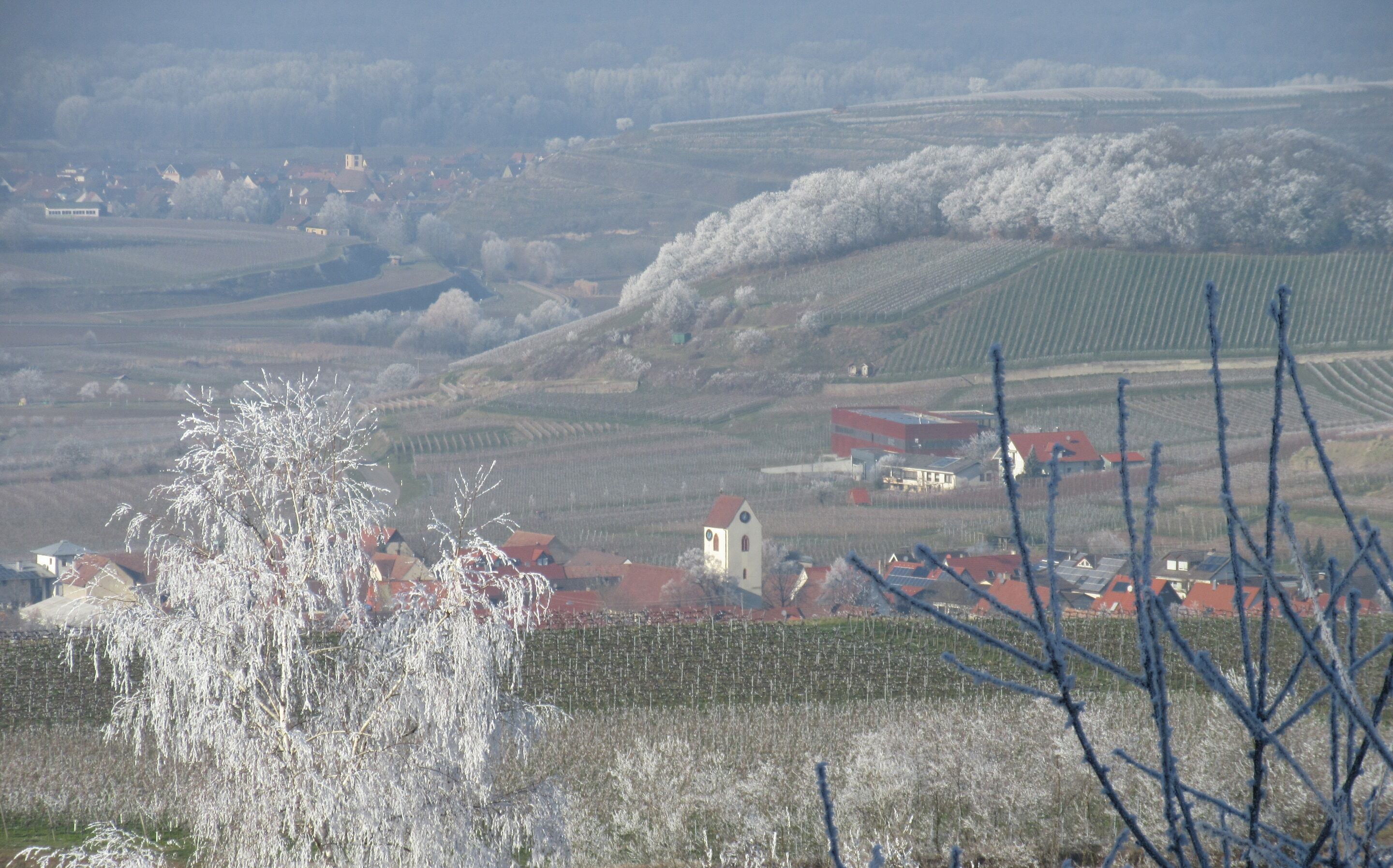 A rural landscape with rolling hills, a small village, and a church.