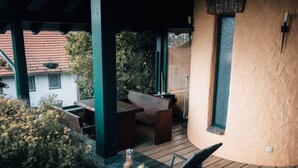 An outdoor patio with wooden furniture, a stone wall, and a view of a mountain.