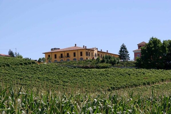 A building with a tiled roof, surrounded by a green field. - Belvilla by OYO Nizza Bilo Sedici Diciotto (Nizza Monferrato)