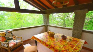 Um banco de madeira com almofada florida, uma mesa com toalha decorada com motivos de frutas e uma cesta.