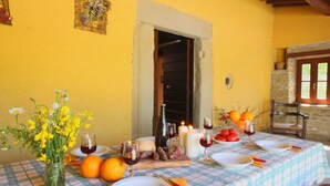 Una mesa de comedor dispuesta con platos, cubiertos, una vela y un jarrón con flores amarillas.