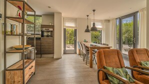 A modern kitchen with wooden shelves and a dining area with a table and chairs. - Beautiful Holiday Home With Terrace (Egmond aan den Hoef)