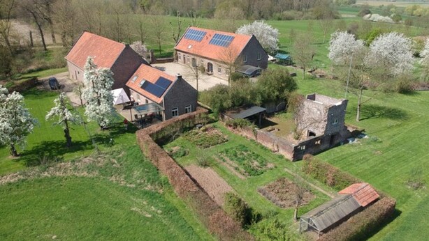 Ein ländliches Anwesen mit mehreren Gebäuden, darunter ein Stall mit Solaranlage, umgeben von grünen Feldern und Bäumen.