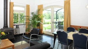 Ein Zimmer mit Kamin, Esstisch, Stühlen und Blick ins Freie.