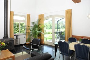 Ein Zimmer mit Kamin, Esstisch, Stühlen und Blick ins Freie.