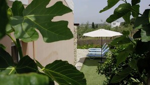 Un patio con un paraguas blanco y sillones azules.