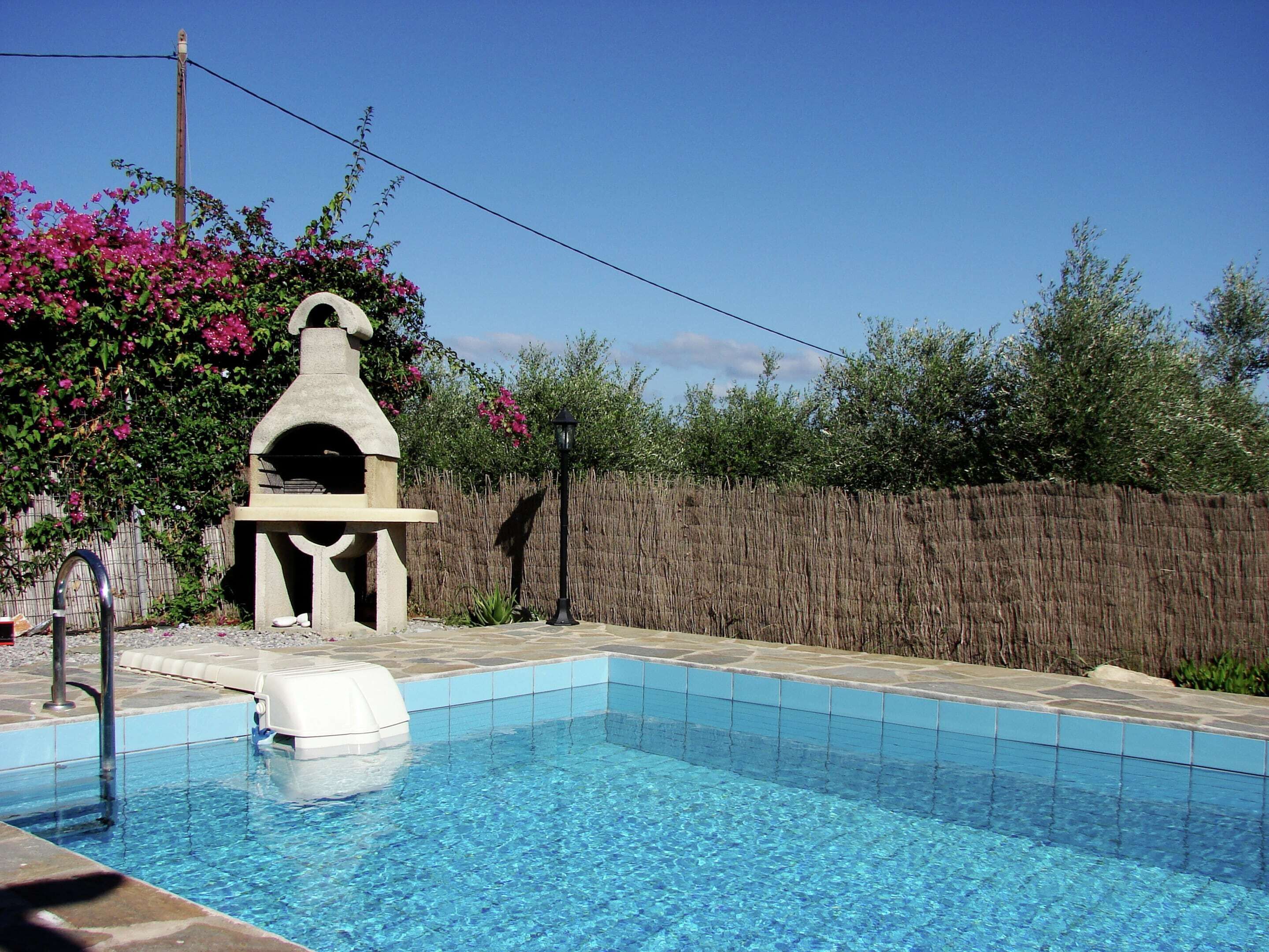 Une piscine dotée d’une structure en pierre et d’une clôture en bois en arrière-plan.
