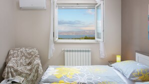 A bedroom with a bed, a chair, a radiator, and a window with a view. - Detached Villa With Private Pool Located on Hill Overlooking Kvarner (Labin)