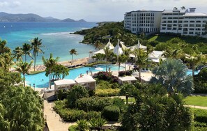 A resort with a pool, palm trees, and a view of the ocean.
