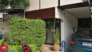 Una scooter roja estacionada frente a un edificio donde se ve un coche azul dentro de un garaje.