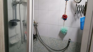 Un baño con puerta de vidrio y ducha con cabezal de ducha manual.