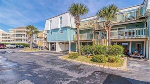 A beachfront hotel with multiple-story buildings, balconies, and palm trees. - Entire Pensacola Beach Condo at Boardwalk (Pensacola Beach)