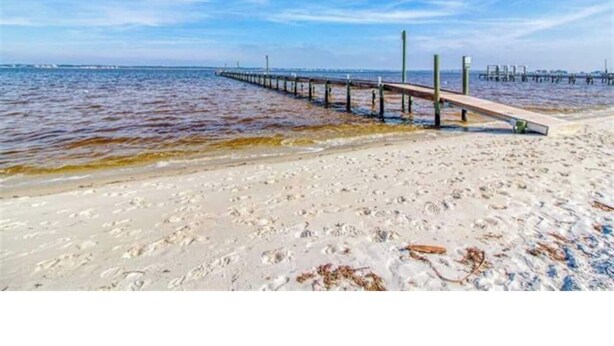 A beach with a wooden pier extending into the water. - Entire Pensacola Beach Condo at Boardwalk (Pensacola Beach)