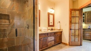 Une salle de bain avec une douche, un meuble-lavabo avec un miroir et une porte en bois.