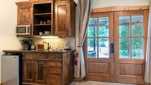 Une cuisine avec des meubles de rangement en bois, un four à micro-ondes, une machine à café et un réfrigérateur.