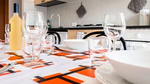 A modern kitchen with a dining table set for a meal, featuring a bottle of white wine, multiple glasses, and a bowl. - Casa Paola 2 - Near the city center (Mestre)