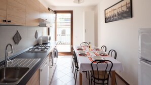 A modern kitchen with a dining area, featuring a kitchen island, stainless steel appliances, and a dining table set for four. - Casa Paola 2 - Near the city center (Mestre)