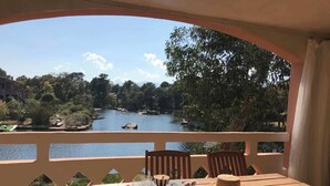 A wooden table with chairs, a view of a river, and a balcony railing. - Charming flat with view on the lagoon (Lecci)