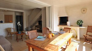 A dining area with a wooden table and chairs, a kitchen with a built-in oven, and a staircase leading to another level. - Charming flat with view on the lagoon (Lecci)