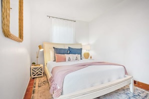 Ein Schlafzimmer mit einem Bett, einem Nachttisch, einer Lampe und einem Spiegel.