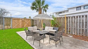 A patio with a round table and chairs, a covered seating area, and a wooden fence. - Walk to Downtown St. Augustine, Boho Chic Bungalow (St. Augustine)