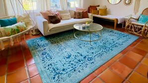 Un salon avec un canapé, une table basse et un tapis à motifs.