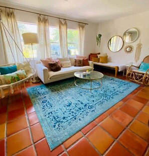 A living room with a sofa, coffee table, and a patterned rug. - Walk to Downtown St. Augustine, Boho Chic Bungalow (St. Augustine)