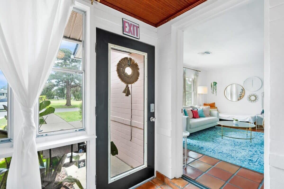 A modern interior with a black-framed door, a white wall, and a blue patterned rug.