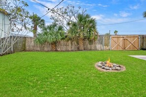 A backyard with a fire pit, a wooden fence, and palm trees. - Walk to Downtown St. Augustine, Boho Chic Bungalow (St. Augustine)