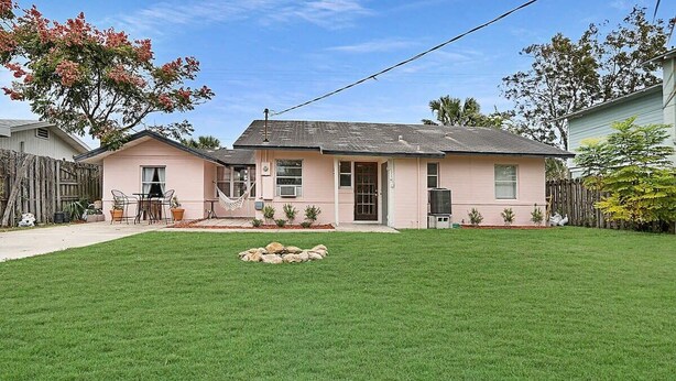 A single-story house with a well-maintained lawn, a small patio with chairs, and a hammock. - Walk to Downtown St. Augustine, Boho Chic Bungalow (St. Augustine)