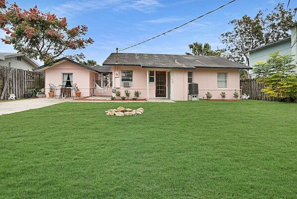 A single-story house with a well-maintained lawn, a small patio with chairs, and a hammock.