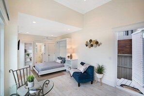 A bedroom with a bed, a blue armchair, a bedside table, and a wall-mounted decoration. - 100 Steps to Beach, Deck w Ocean View, Beach Gear (St. Augustine)