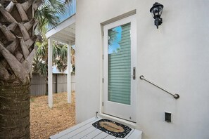 A white door with a green shutter, a black wall-mounted light fixture, and a metal handrail. - 100 Steps to Beach, Deck w Ocean View, Beach Gear (St. Augustine)
