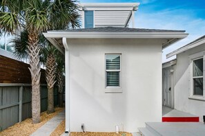 A small, single-story house with a white exterior, a small window with shutters, and a red step leading to the front door. - 100 Steps to Beach, Deck w Ocean View, Beach Gear (St. Augustine)