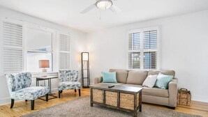 A living room with a ceiling fan, a sofa, two armchairs, a coffee table, and a floor lamp.