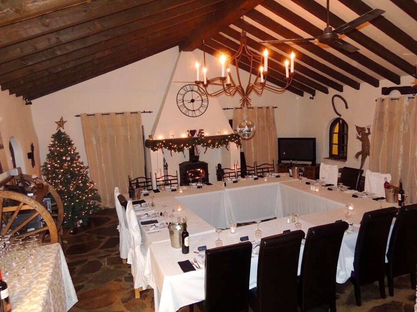 Un coin repas avec une grande table dressée pour le repas, un sapin de Noël et une cheminée.