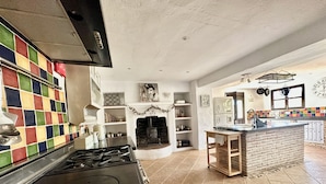 A kitchen with a tiled backsplash, a stove, a fireplace, and a breakfast bar. - Large traditional CORTIJO, Large Private pool, Ping Pong table , family/groups (Malaga)