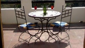 A patio with a round table and two chairs, overlooking a mountainous landscape. - Large traditional CORTIJO, Large Private pool, Ping Pong table , family/groups (Malaga)