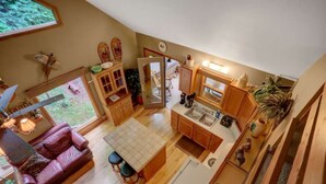 Cozinha compacta com armários de madeira, área de jantar com mesa e cadeiras, e vista para o exterior através de uma janela.