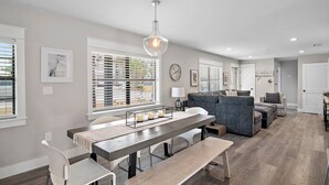 Moderni olohuone, jossa on ruokailutila, harmaat seinät ja suuri ikkuna, jossa on sälekaihtimet.