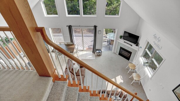 A spacious living area with a fireplace, a television, and a large window overlooking a deck. - The Hideaway -Raystown Lake Vacation Rentals, Aunt Susie's (Hesston)