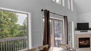 A spacious balcony with a wooden table and chairs, a TV, and a fireplace. - The Hideaway -Raystown Lake Vacation Rentals, Aunt Susie's (Hesston)
