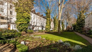 A courtyard with a lawn, trees, and buildings with multiple windows and balconies. - 12 London Street Apartments (London)