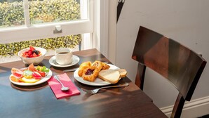 A breakfast table with croissants, bread, fruit, and a cup of coffee. - 12 London Street Apartments (London)
