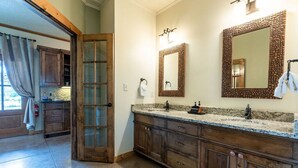 Un baño con un tocador de madera, dos espejos y un perchero para toallas.