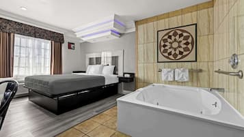 Una habitación de hotel moderna con una cama grande, una zona de estar independiente, una bañera y un panel decorativo en la pared.