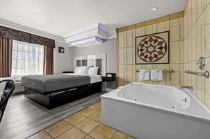 Una habitación de hotel moderna con una cama grande, una zona de estar independiente, una bañera y un panel decorativo en la pared.