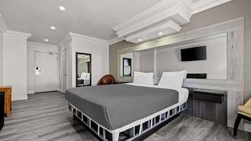 Una habitación de hotel moderna con una cama grande, una televisión de pantalla plana, un escritorio y una silla.