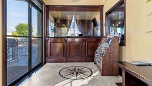 A hotel lobby with a large window, a wooden reception desk, and a wall-mounted display of brochures. - Rodeway Inn Santa Ana - Garden Grove (Santa Ana)