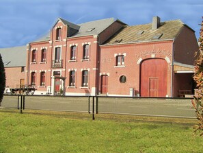 A red brick building with a large wooden door and multiple windows.